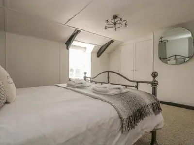 a bedroom with a white bed with a mirror at Boundys House in St Ives
