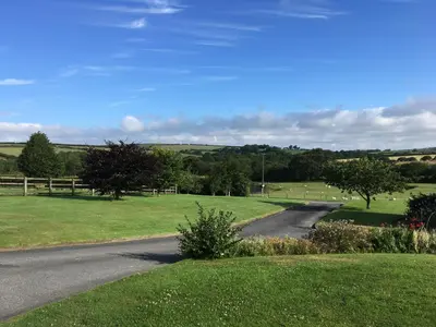 a road in the middle of a green field at Maple & Beech Barns in Truro