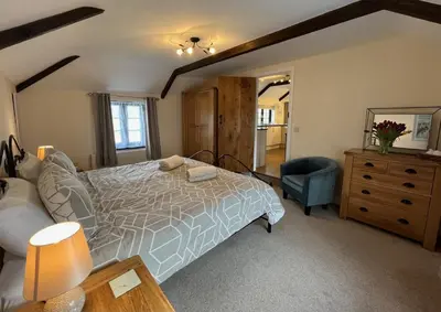 a bedroom with a bed and a chair and a dresser at Maple & Beech Barns in Truro