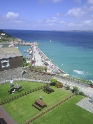 a view of the ocean and a beach with cars at Seashells in Newquay