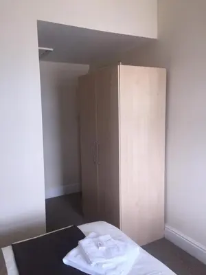 a bedroom with a wardrobe and a bed with white sheets at Seashells in Newquay