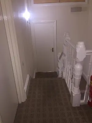 a hallway with a stairway with a white door at Seashells in Newquay