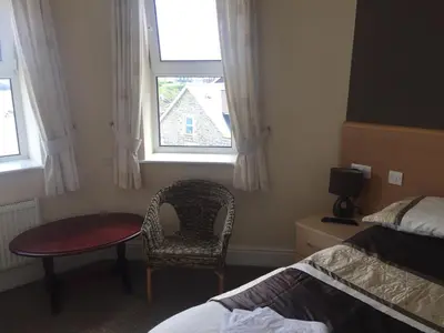 a bedroom with a bed and a chair and a window at Seashells in Newquay
