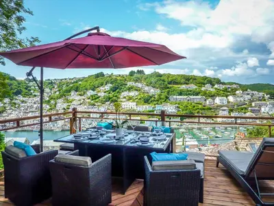 a table and chairs with an umbrella on a deck at Looe Self Catering in Looe