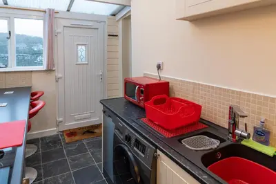 a kitchen with a washing machine and a red microwave at Looe Self Catering in Looe