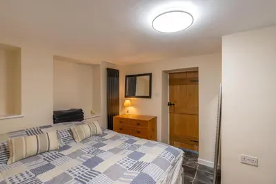 a bedroom with a bed and a dresser and a lamp at Looe Self Catering in Looe