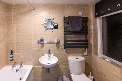 a bathroom with a sink and a toilet and a mirror at Looe Self Catering in Looe