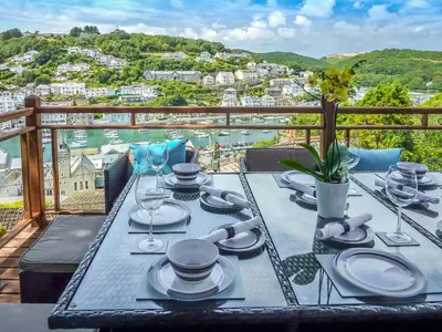 a table with plates and wine glasses on a balcony at Looe Self Catering in Looe