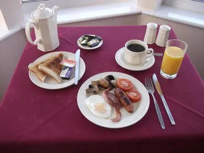 a table with two plates of breakfast foods and a cup of coffee at Kenton in Newquay