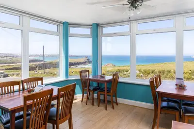 a dining room with tables and chairs and windows at Kenton in Newquay