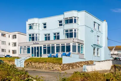 a white building with blue chairs in front of it at Kenton in Newquay