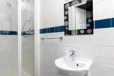 a bathroom with a sink and a mirror and a shower at Kenton in Newquay