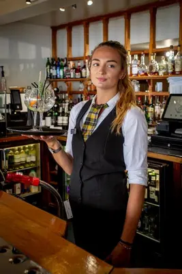 a woman standing behind a bar with a martini glass at The Hannafore Point Hotel in Looe