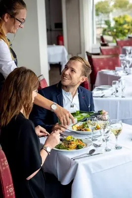 a man and woman sitting at a table with a plate of food at The Hannafore Point Hotel in Looe