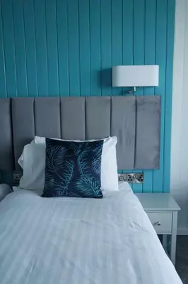 a bedroom with a bed with a blue wall at The Hannafore Point Hotel in Looe