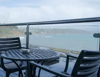 a table and chairs on a balcony with a view of the water at The Hannafore Point Hotel in Looe