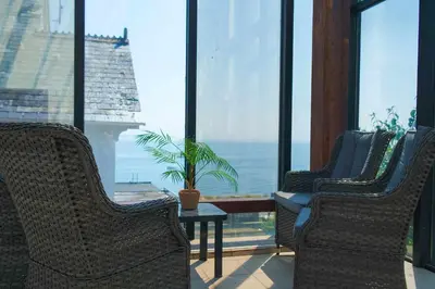 three chairs and a table in a room with windows at The Hannafore Point Hotel in Looe