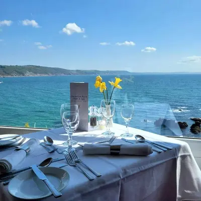 a table with a white table cloth with a view of the ocean at The Hannafore Point Hotel in Looe