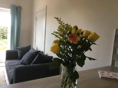 a vase filled with yellow roses in a living room at Little Fernleigh in Perranporth
