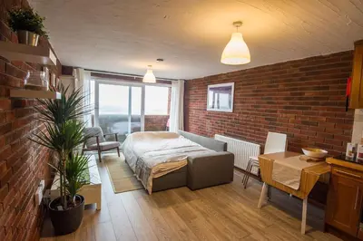 a bedroom with a bed and a brick wall at South Fistral View Apartment in Newquay