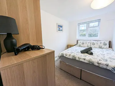 a bedroom with a bed and a lamp on a dresser at South Fistral View Apartment in Newquay