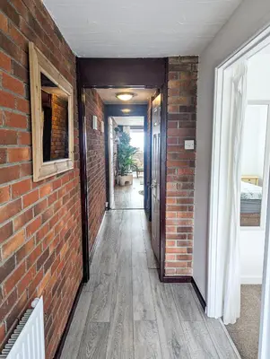 an empty hallway with a brick wall and a door at South Fistral View Apartment in Newquay