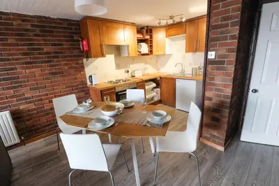 a kitchen with a wooden table and white chairs at South Fistral View Apartment in Newquay