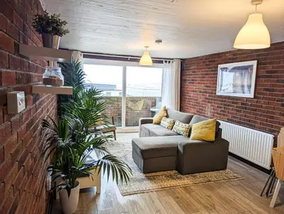 a living room with a couch and a brick wall at South Fistral View Apartment in Newquay