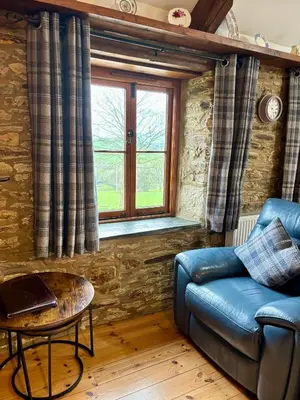 a living room with a blue couch and a window at Tregolls Farm Cottages in Wadebridge