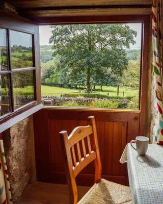 a table and a chair in a room with a window at Tregolls Farm Cottages in Wadebridge