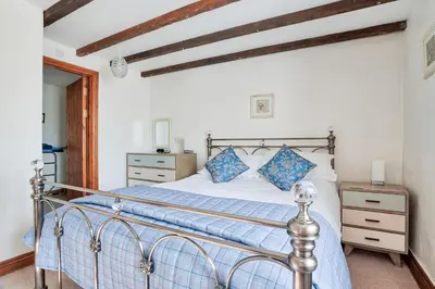 a bedroom with a bed with blue pillows at Tregolls Farm Cottages in Wadebridge
