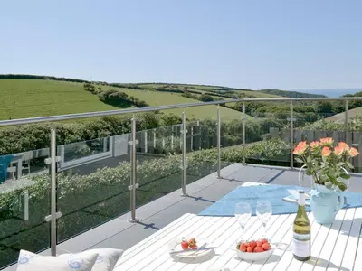 a patio with a table and a bottle of wine at Roskear in Saint Gennys