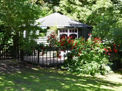 a gazebo behind a fence with red flowers at Beach Retreat - Ukc2322 in Carbis Bay