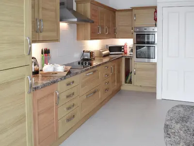 a kitchen with wooden cabinets and stainless steel appliances at Seaglass in Marazion
