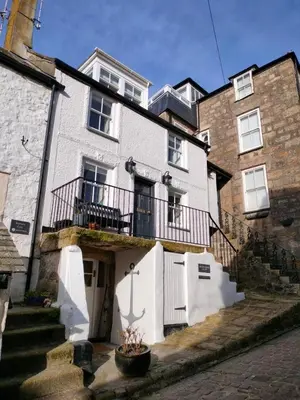 a large white house with a balcony and stairs at Anchorage Guest House, St Ives in St Ives