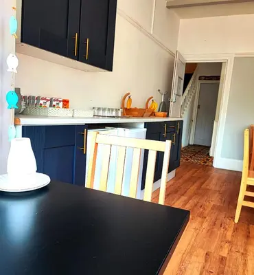 a kitchen with blue cabinets and a black table and chairs at St Breca in Newquay