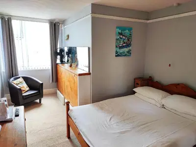a bedroom with a bed and a chair and a window at St Breca in Newquay