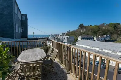a wooden deck with a table and chairs on a balcony at Fisherman's Cottage in Saint Mawes