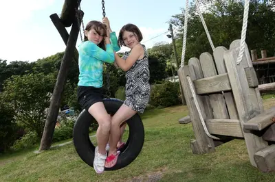 two young children playing on a tire swing at Tehidy Holiday Park in Illogan