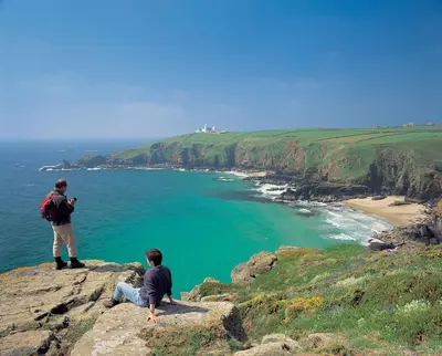 two men standing on top of a cliff looking at the ocean at Tehidy Holiday Park in Illogan
