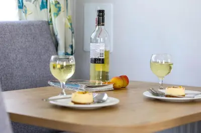 a table with two glasses of white wine and cheese at Tehidy Holiday Park in Illogan