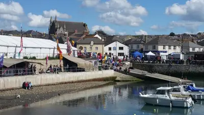 a group of people walking down a dock with boats in the water at Mandeley Guest House in Helston