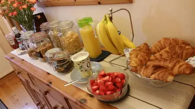 a table with croissants bananas and other breakfast foods at Mandeley Guest House in Helston
