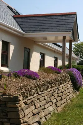 a house with a retaining wall with purple flowers at Mandeley Guest House in Helston