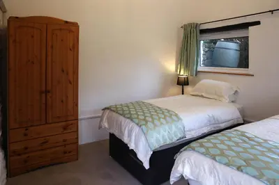 a bedroom with two beds and a dresser and a window at Little Trewin in Helston