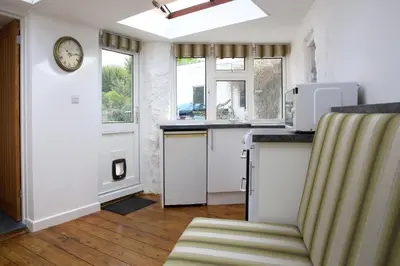 a kitchen with a counter and a clock on the wall at Little Trewin in Helston