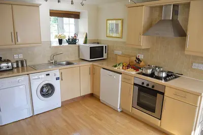 a kitchen with a washer and a sink and a dishwasher at Mews Cottage in Cury