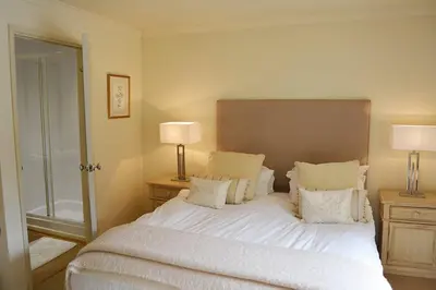 a bedroom with a large white bed with two lamps at Mews Cottage in Cury