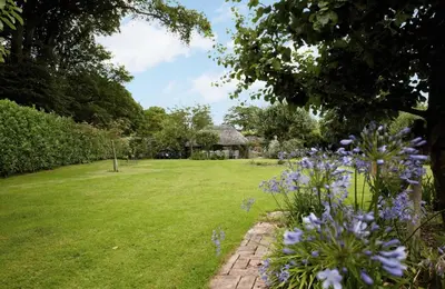 a garden with purple flowers and a house at Spring Water Barn in Helston