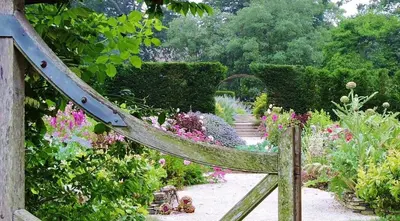 a wooden gate leading to a garden with flowers at Spring Water Barn in Helston